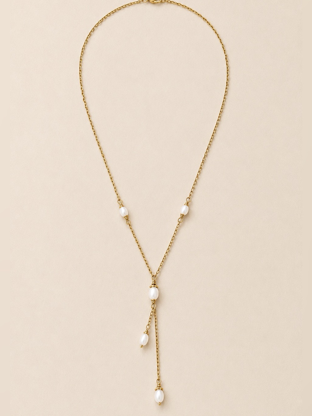 Delicate gold-tone lariat necklace with soft pearl-like bead accents